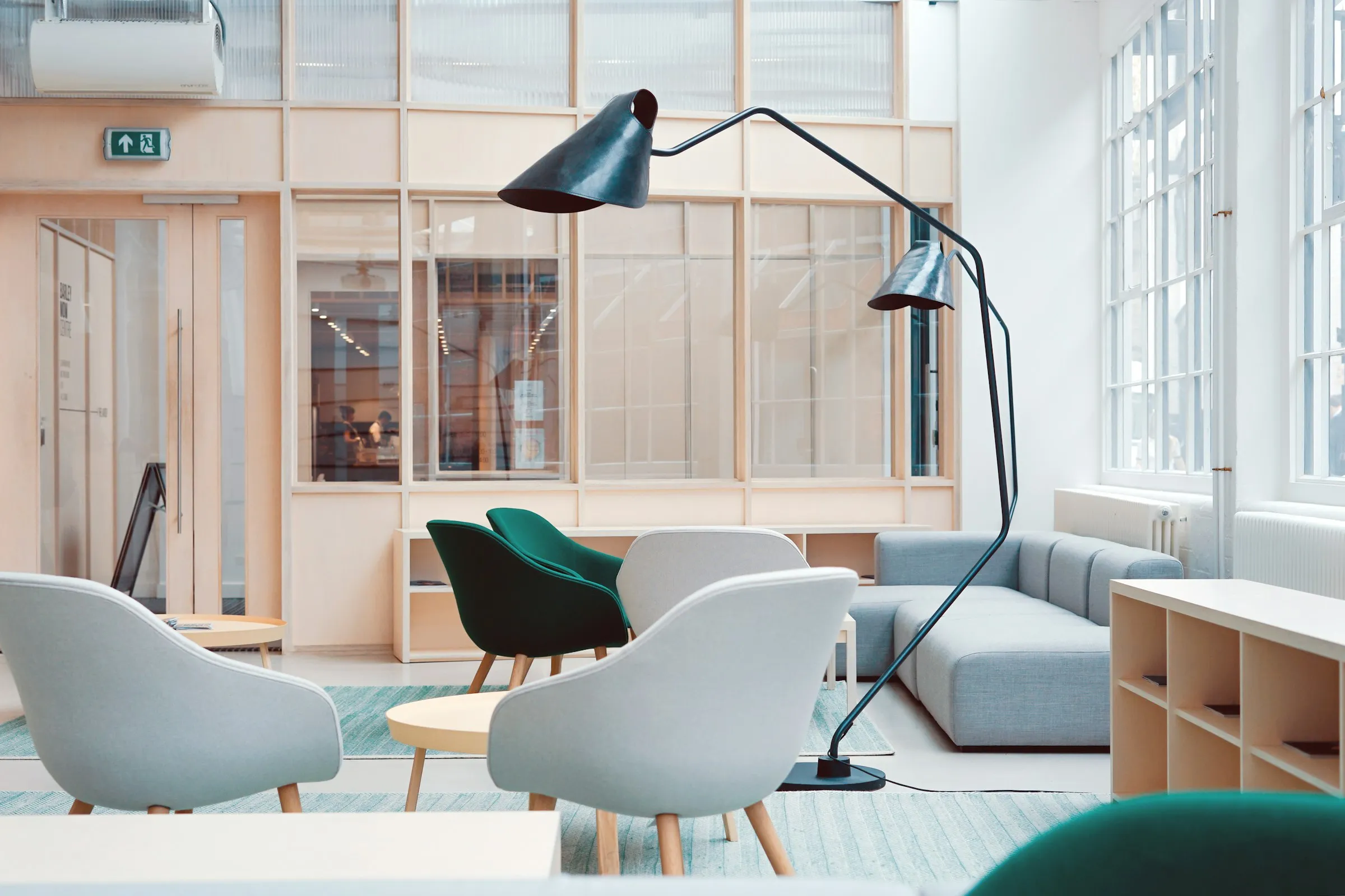 A quiet, well-lit office lounge with soft seating arranged beside tall windows.